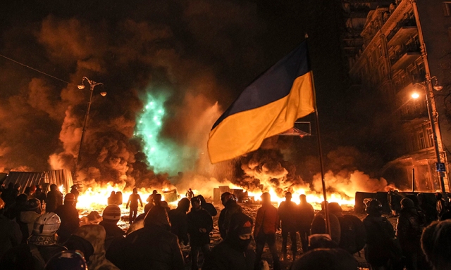 Pro-European integration protesters gather in front of burning tyres during clashes with riot police in Kiev