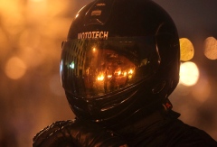 A pro-European integration protester looks on through a visor reflecting burning tyres at the site of clashes with riot police in Kiev